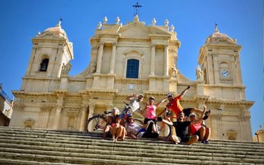 Cyklister vid kyrka i Noto