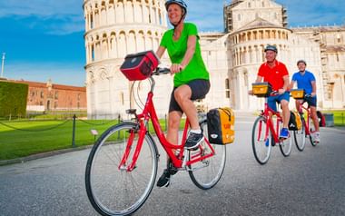 Cyklister vid lutande tornet i Pisa