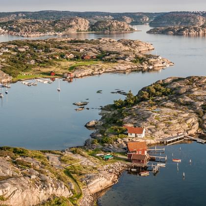 Luftaufnahme von Göteborgs Schärengarten mit Felsinseln, roten Holzhäusern, ruhigem blauen Wasser und Granitformationen.