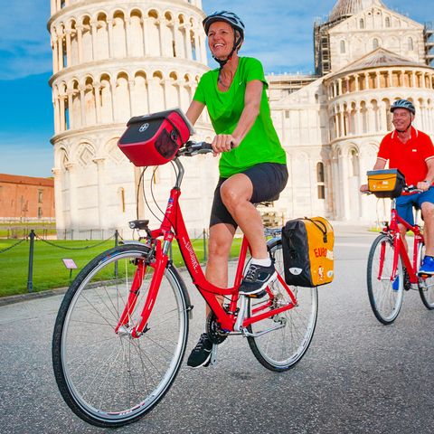 Cyklister vid lutande tornet i Pisa