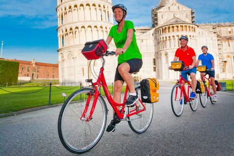 Cyklister vid lutande tornet i Pisa
